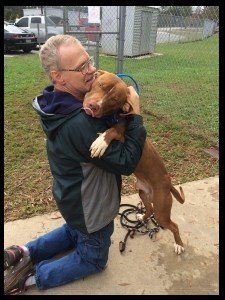 A man holding his dog in the air.