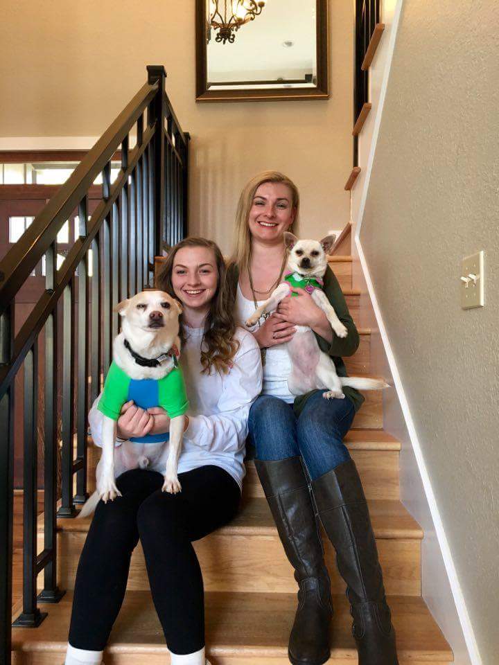 Two women and a dog sitting on the stairs.